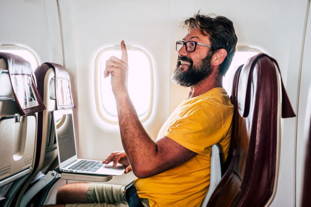man on computer on airplane