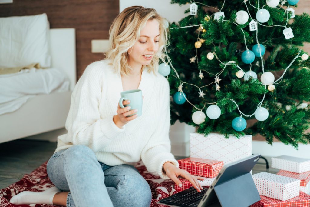 woman working by Christmas tree with coffee